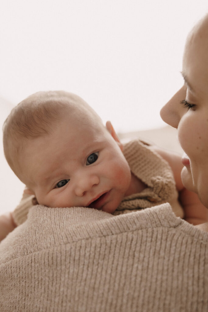Achtsame und liebevoll begleitete Neugeborenen-Fotografie in Engelskirchen und Umgebung. Baby schaut über Mamas Schulter.
